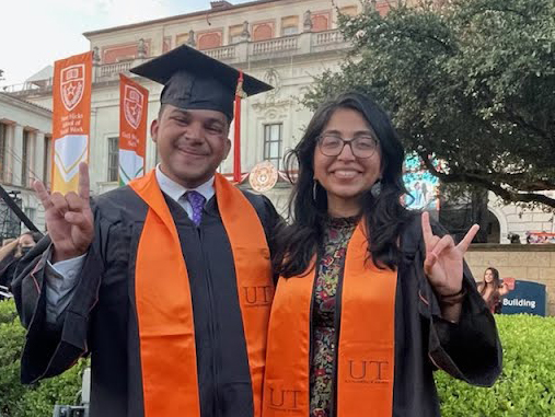 TX engineering students Hamzah Moin and Devika Manish smiling in graduation regalia doing hook 'em horns hand signs