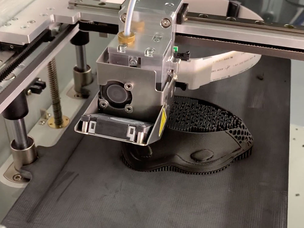 3D printer printing a mask with black plastic