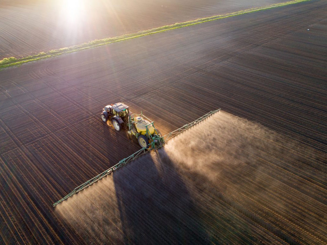 tractor spreading fertilizer over farmland