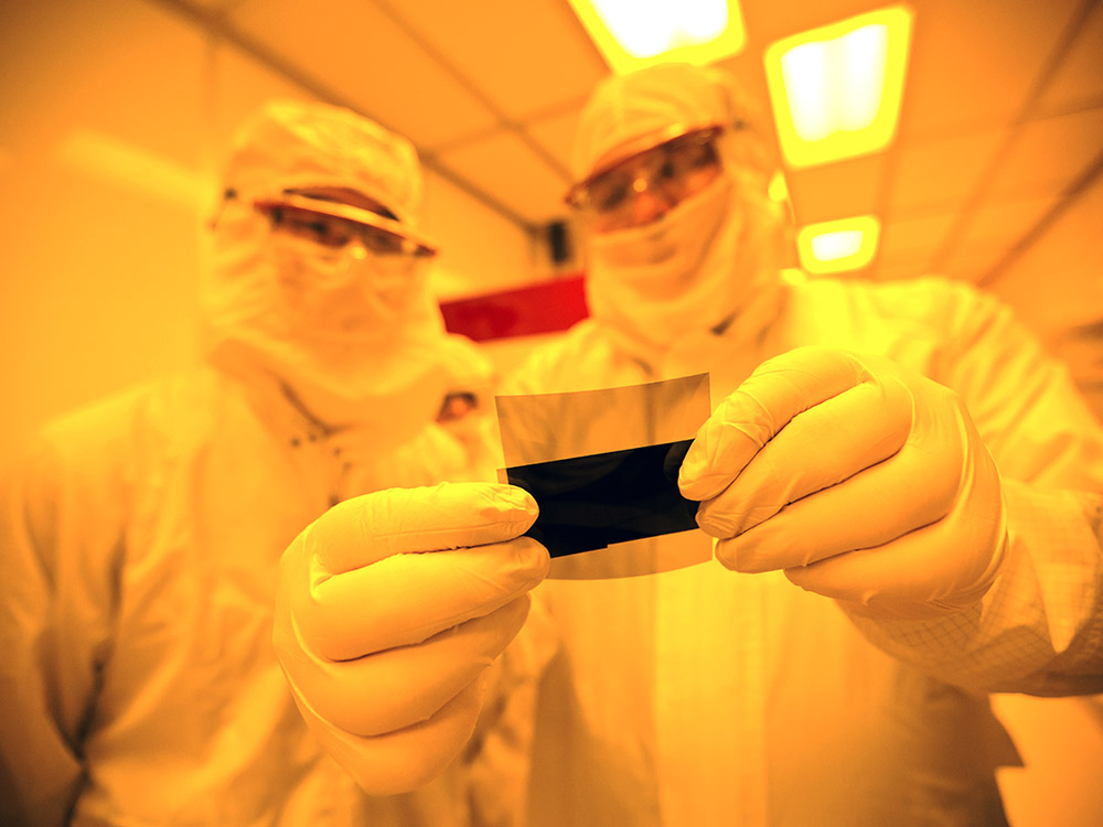 researchers in clean room examining a material