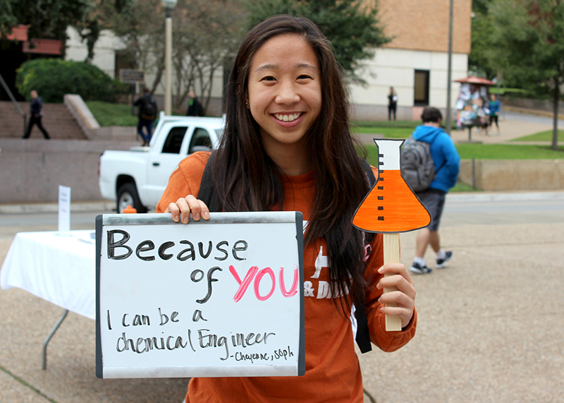 Smiling UT Engineering student holding 'thank you' sign at Donor Thanks Day