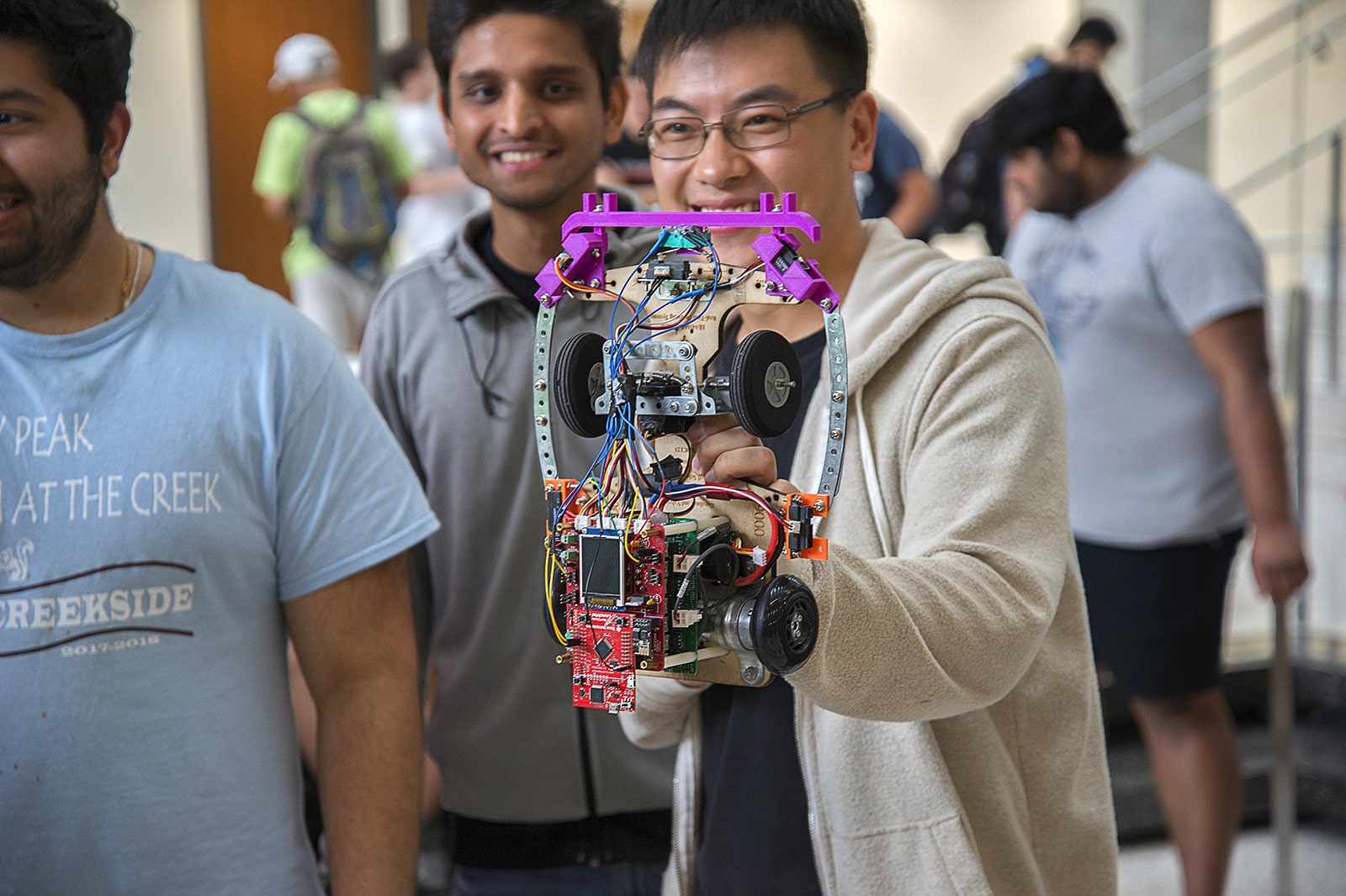 smiling students holding complicated robotics device